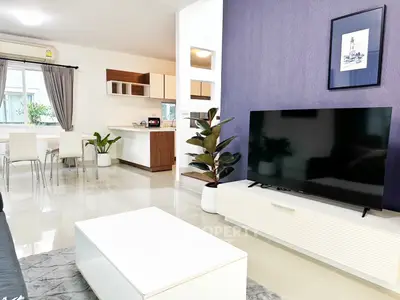 Modern living room with sleek TV, open kitchen, and stylish decor