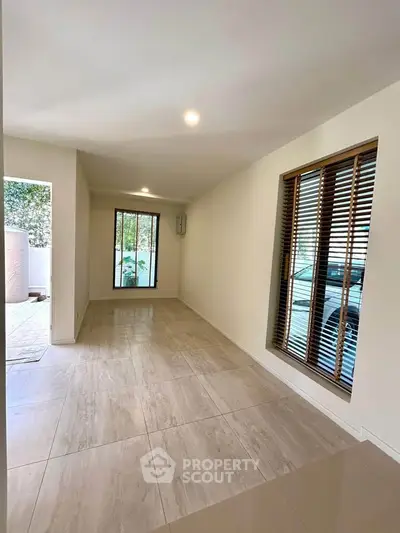Spacious modern living room with large windows and elegant tile flooring
