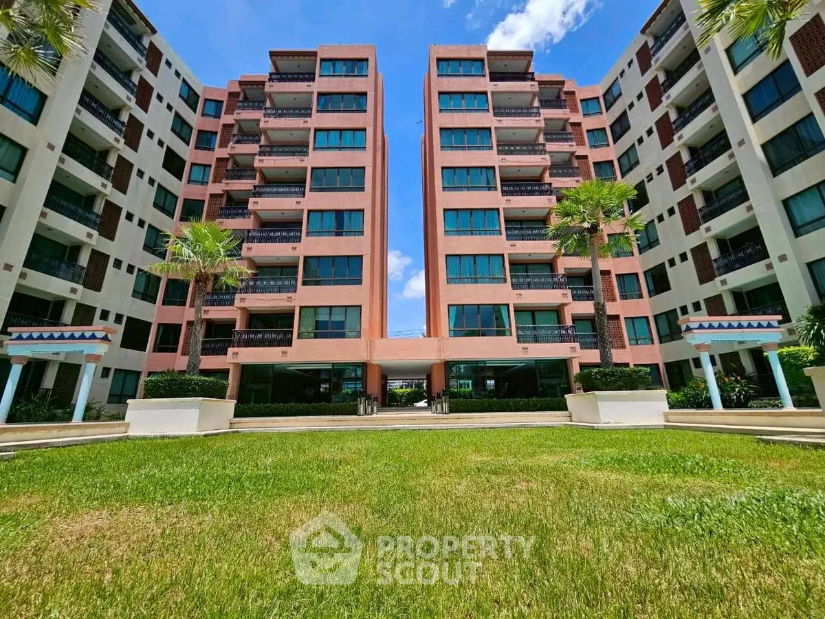 Modern apartment complex with lush green lawn and clear blue sky.