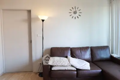 Cozy living room with brown leather sofa and modern floor lamp, perfect for relaxation.