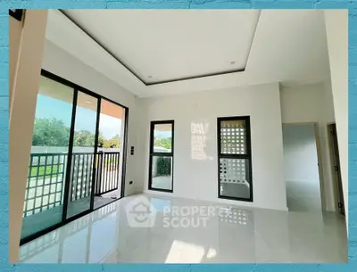 Spacious modern living room with large windows and balcony access, offering abundant natural light and serene views.