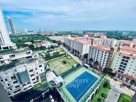 Stunning aerial view of modern residential complex with tennis court and lush surroundings.
