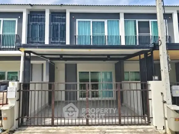 Modern townhouse exterior with gated parking area and large windows.
