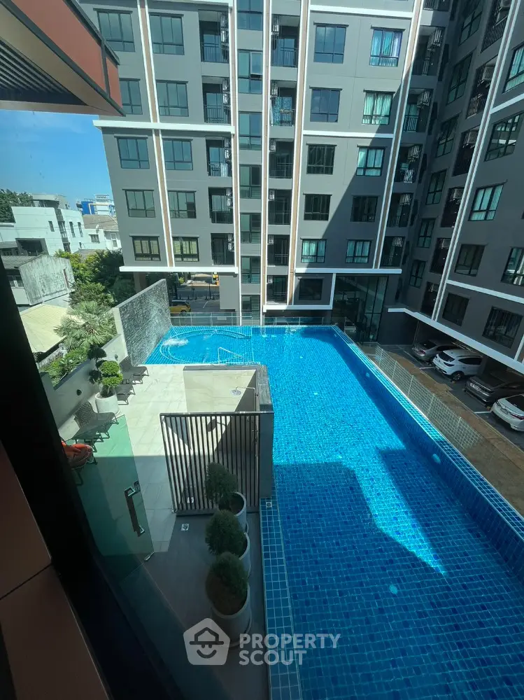 Modern apartment building with a stunning blue swimming pool view from a high angle.