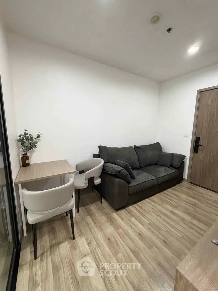 Modern living room with cozy sofa and dining area, featuring sleek wooden flooring and minimalist decor.
