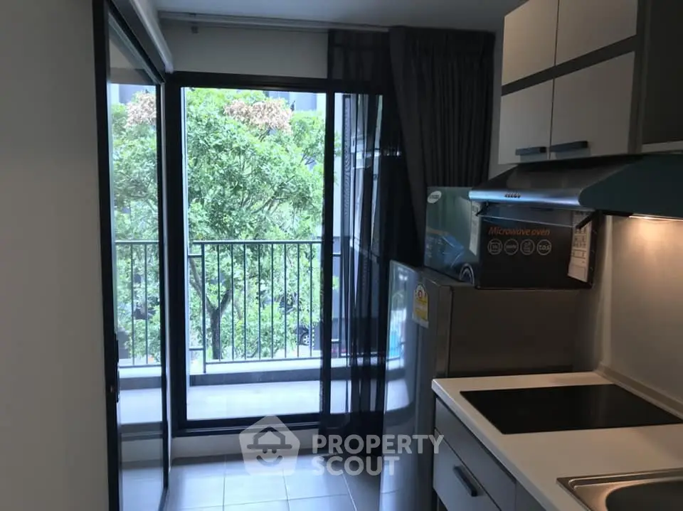 Modern kitchen with balcony view and sleek appliances in urban apartment.