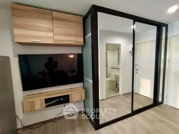 Modern living room with sleek TV setup and mirrored closet doors.