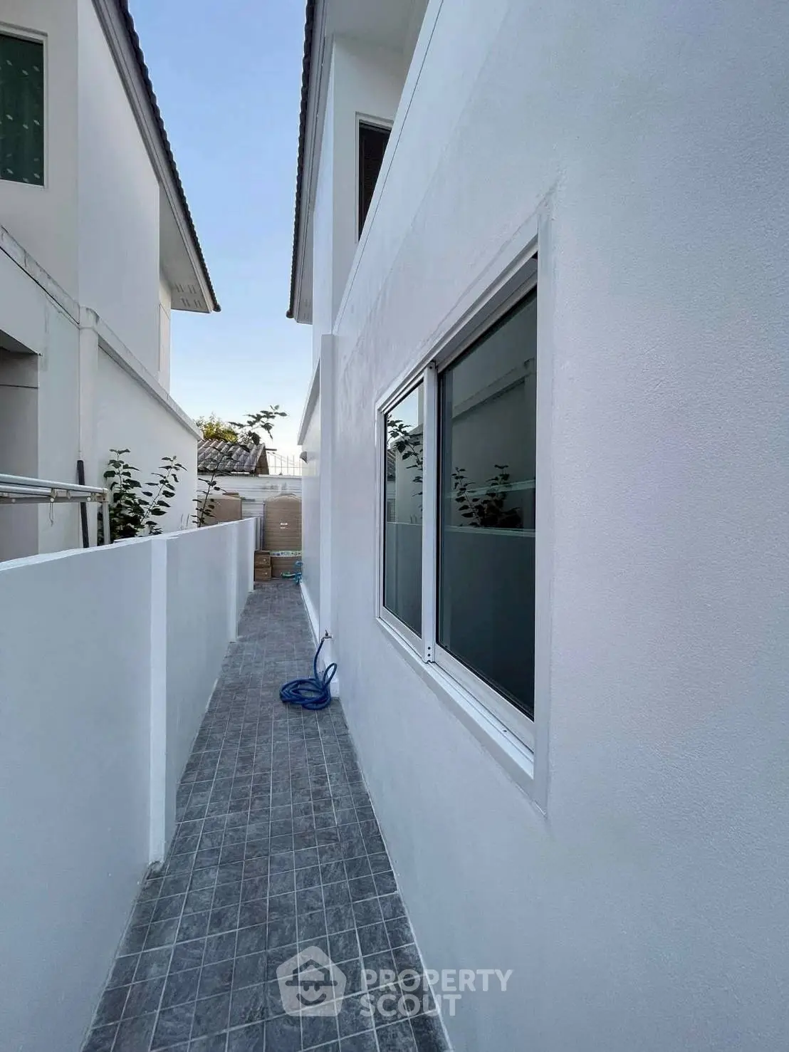 Modern exterior side pathway of a white house with tiled flooring