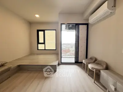 Modern living room with balcony access and air conditioning, featuring sleek wooden flooring and neutral tones.