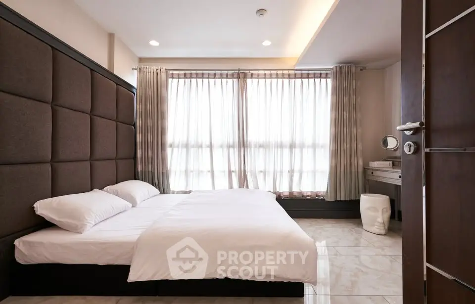 Spacious bedroom with modern decor and large windows for natural light
