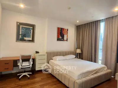 Modern bedroom with stylish decor and large window offering city views, featuring a comfortable bed and workspace.