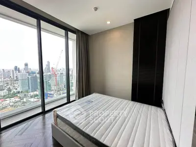 Modern bedroom with floor-to-ceiling windows offering stunning city views in a high-rise apartment.