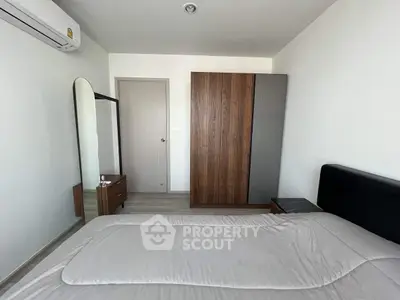 Modern bedroom with sleek furniture and minimalist design, featuring a large wardrobe and air conditioning.