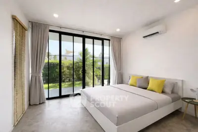 Spacious bedroom with large windows and garden view, featuring modern decor and air conditioning.