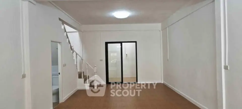 Spacious unfurnished living room with staircase and glass door, ideal for customization.