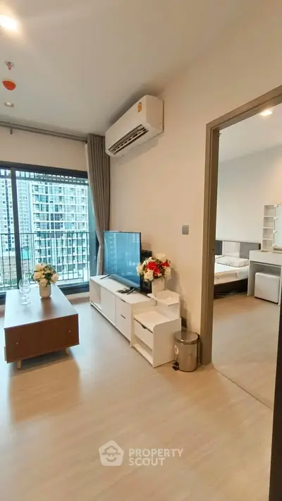 Modern living room with TV and view of bedroom in high-rise apartment