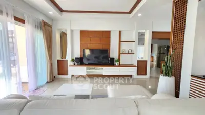 Spacious modern living room with elegant decor and large TV, perfect for relaxation.