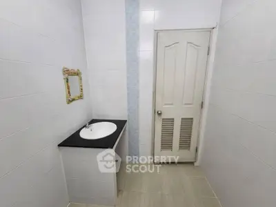 Minimalist bathroom with white tiles and a simple vanity unit.
