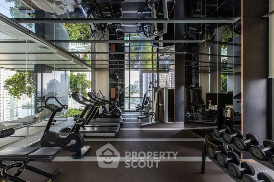 Luxurious gym with modern equipment and mirrored walls in high-end residential building.