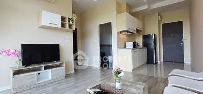 Modern living room with open kitchen, featuring sleek furniture and natural light.