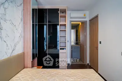 Modern bedroom with built-in wardrobe and marble accent wall in stylish apartment.