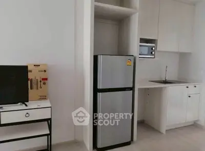 Modern kitchen with sleek fridge and built-in microwave in compact apartment.