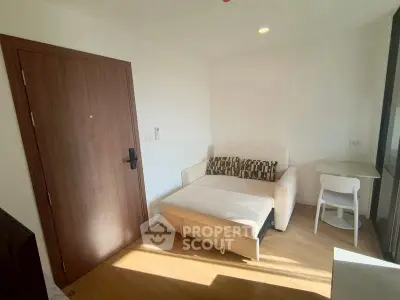Cozy living room with natural light, featuring a comfortable sofa and wooden flooring.