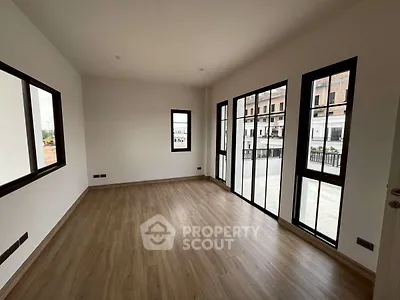 Spacious empty room with large windows and wooden flooring, perfect for customization.