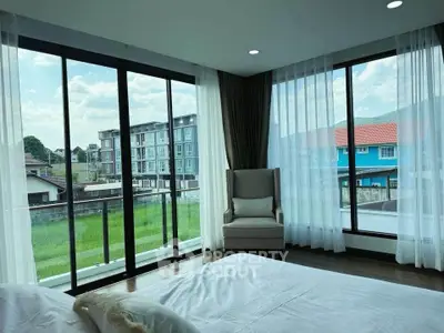 Spacious bedroom with large windows offering a stunning view of the neighborhood and lush greenery.