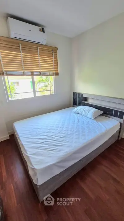 Cozy bedroom with natural light and modern air conditioning unit, perfect for relaxation.