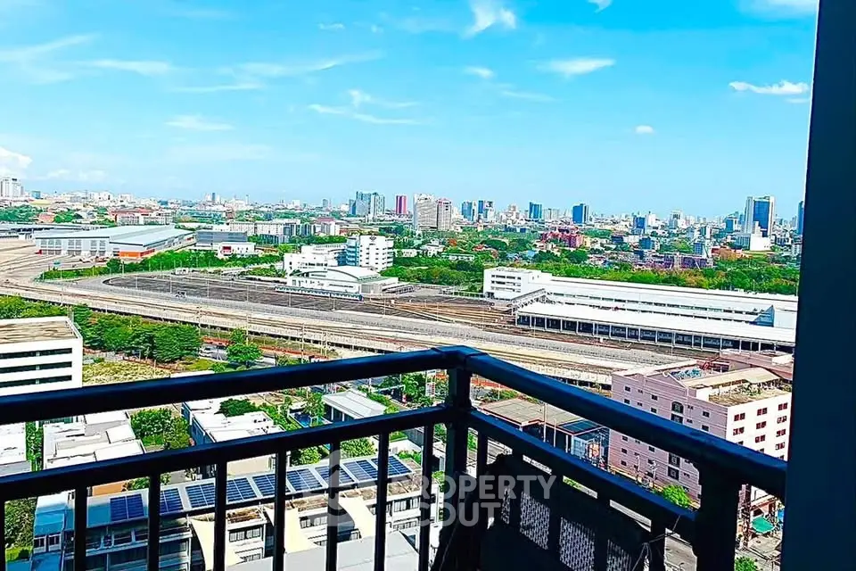 Stunning cityscape view from a high-rise balcony with clear blue skies.