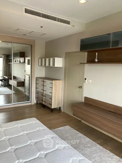 Spacious bedroom with modern furniture and mirrored closet doors in a stylish apartment.