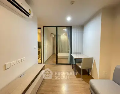 Modern apartment interior with open living and dining area, featuring sleek furniture and wooden flooring.