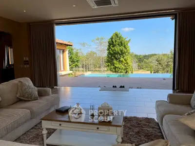 Luxurious living room with open view to private pool and lush greenery, perfect for relaxation and entertaining.