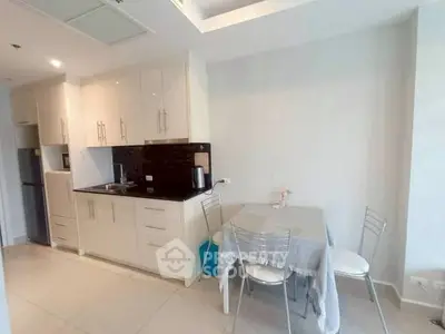 Modern kitchen with sleek cabinets and dining area in a bright apartment.