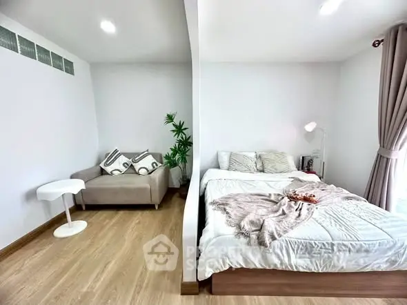 Cozy bedroom with modern decor and natural light, featuring a comfortable bed and stylish seating area.