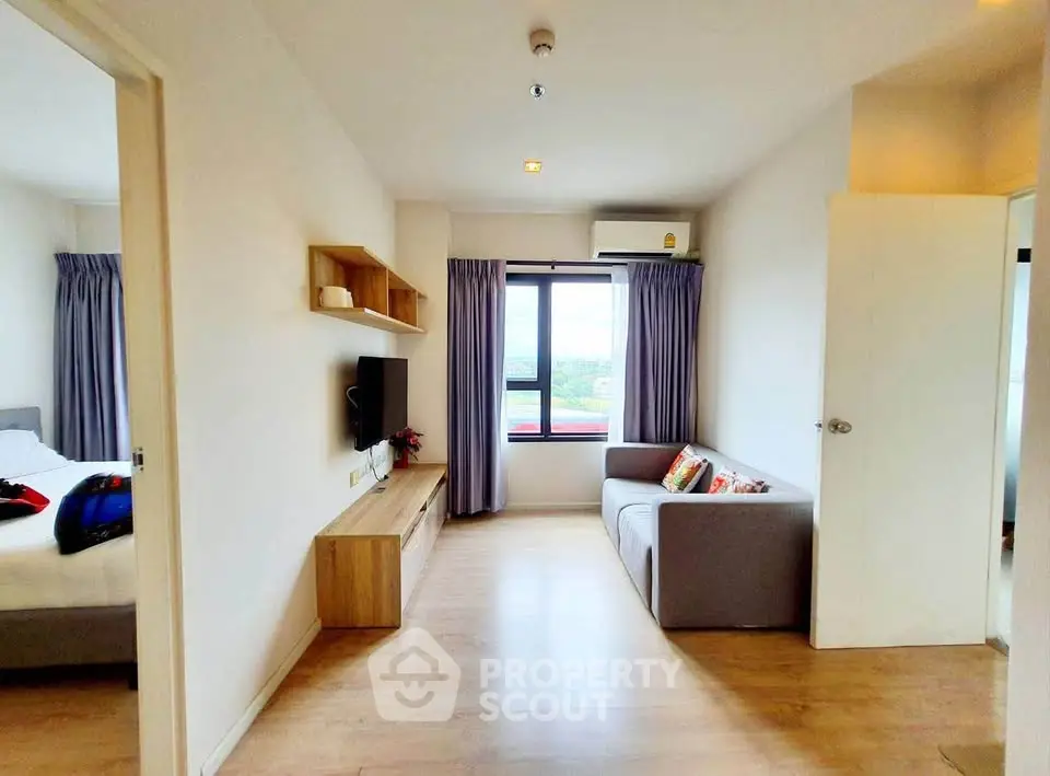 Modern living room with cozy sofa and wall-mounted TV, adjacent to a bright bedroom.