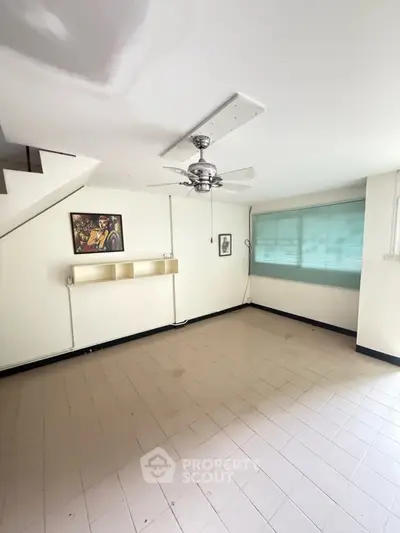 Spacious living room with ceiling fan and natural light, ideal for modern living.