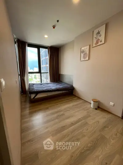 Cozy bedroom with wooden flooring and city view, perfect for urban living.