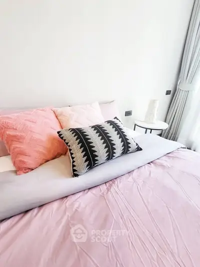 Cozy bedroom with stylish pillows and soft pink bedding, perfect for relaxation and comfort.