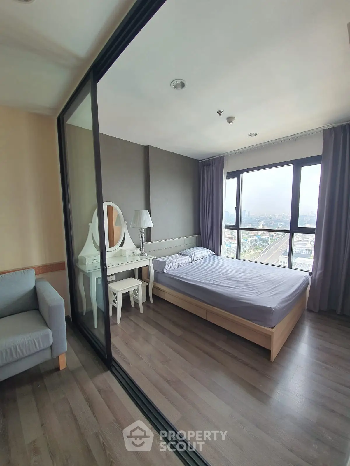 Modern bedroom with city view, featuring a cozy bed and elegant vanity set.