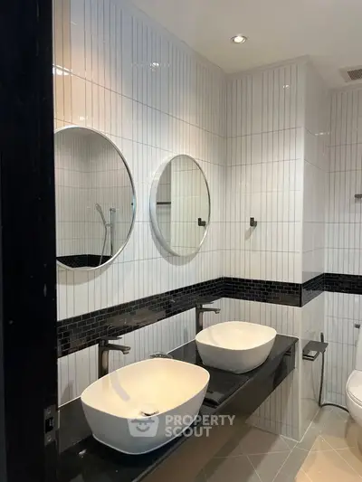 Modern bathroom with dual sinks and stylish black and white tile design.