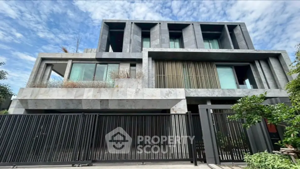 Modern luxury home with sleek architectural design and large windows, surrounded by lush greenery.