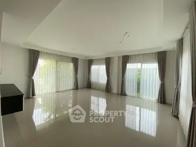 Spacious empty living room with large windows and elegant curtains
