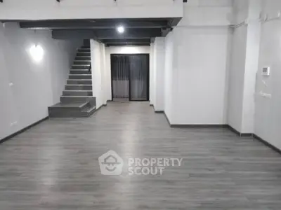 Spacious modern interior with sleek flooring and staircase, ideal for versatile living or office space.