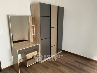 Modern bedroom with stylish wardrobe and vanity on wooden flooring.