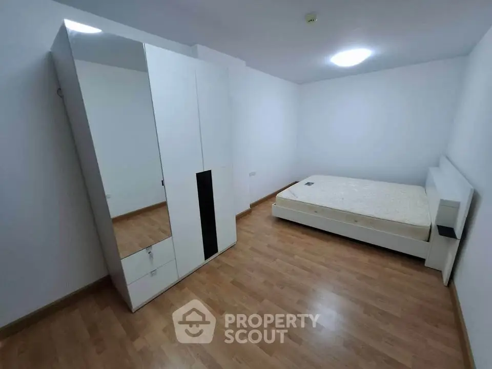Spacious minimalist bedroom with wooden flooring and modern furniture