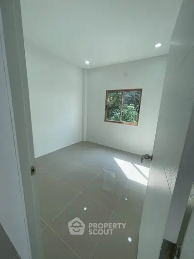 Bright empty room with tiled floor and window view of greenery, ideal for customization.