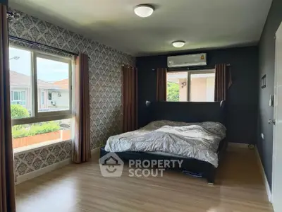 Spacious bedroom with modern decor and large windows offering natural light.