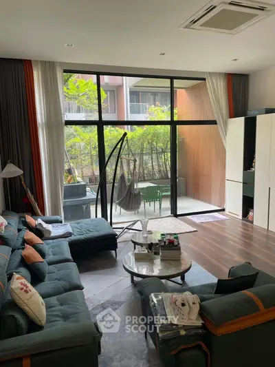 Spacious living room with modern decor and large windows opening to a private garden patio.